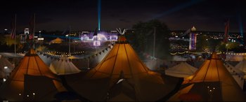 Movie still from “Kingsman: The Golden Circle” (2017), directed by Matthew Vaughn – A teepee is lit up at night in a park; Extreme Wide shot, High angle