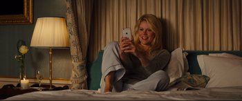 Movie still from “Kingsman: The Golden Circle” (2017), directed by Matthew Vaughn – A woman sitting on a bed looking at a cell phone; Medium shot, High angle