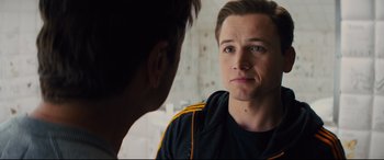 Movie still from “Kingsman: The Golden Circle” (2017), directed by Matthew Vaughn – A young man looking at another young man in front of a brick wall; Close Up shot, Over the shoulder angle