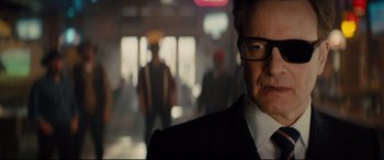 Movie still from “Kingsman: The Golden Circle” (2017), directed by Matthew Vaughn – A person wearing a suit and glasses; Close Up shot, Over the shoulder angle