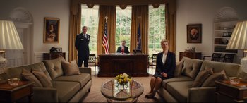 Movie still from “Kingsman: The Golden Circle” (2017), directed by Matthew Vaughn – Three people sitting at a desk in a room; Wide shot, Low angle