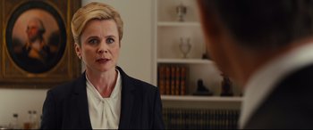 Movie still from “Kingsman: The Golden Circle” (2017), directed by Matthew Vaughn – A woman wearing a suit is looking into the mirror; Close Up shot, Over the shoulder angle