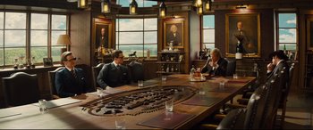 Movie still from “Kingsman: The Golden Circle” (2017), directed by Matthew Vaughn – Two men sitting at a table in front of a painting; Wide shot, Over the shoulder angle