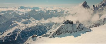 Movie still from “Kingsman: The Golden Circle” (2017), directed by Matthew Vaughn – A view of a snowy mountain range with a ski lodge on top of it; Extreme Wide shot, High angle
