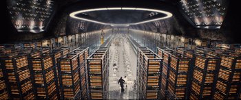 Movie still from “Kingsman: The Golden Circle” (2017), directed by Matthew Vaughn – A man standing in front of stacks of books in a library; Extreme Wide shot, High angle