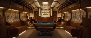 Movie still from “Kingsman: The Golden Circle” (2017), directed by Matthew Vaughn – Two people sitting at a pool table in a room; Wide shot, High angle