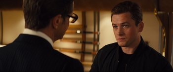 Movie still from “Kingsman: The Golden Circle” (2017), directed by Matthew Vaughn – A man in a black shirt is looking at another man in a black suit; Close Up shot, Over the shoulder angle
