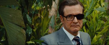 Movie still from “Kingsman: The Golden Circle” (2017), directed by Matthew Vaughn – A person wearing a suit and glasses; Close Up shot, Over the shoulder angle