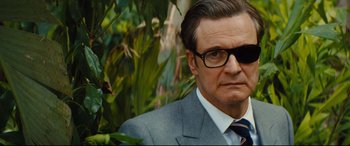 Movie still from “Kingsman: The Golden Circle” (2017), directed by Matthew Vaughn – A person wearing a suit and glasses; Close Up shot, Low angle