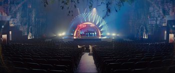 Movie still from “Kingsman: The Golden Circle” (2017), directed by Matthew Vaughn – An empty auditorium with rows of chairs and a stage; Extreme Wide shot, High angle