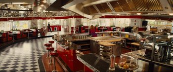 Movie still from “Kingsman: The Golden Circle” (2017), directed by Matthew Vaughn – A restaurant kitchen with red counters and red stools; Wide shot, High angle