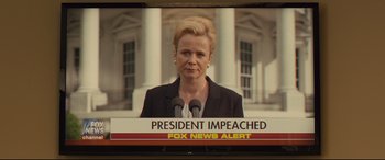 Movie still from “Kingsman: The Golden Circle” (2017), directed by Matthew Vaughn – A television screen showing a news program with a news story about a president impeached; Close Up shot, Over the shoulder angle