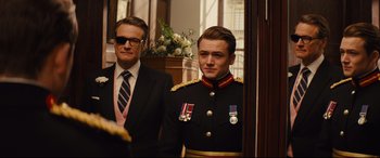 Movie still from “Kingsman: The Golden Circle” (2017), directed by Matthew Vaughn – A man in a suit standing next to another man in a uniform; Medium shot, Over the shoulder angle