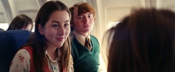 Movie still from “Licorice Pizza” (2021), directed by Paul Thomas Anderson – A girl and a boy sitting next to each other on a plane; Close Up shot, Over the shoulder angle