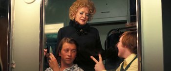 Movie still from “Licorice Pizza” (2021), directed by Paul Thomas Anderson – An older woman standing in front of two young people; Medium shot, Over the shoulder angle