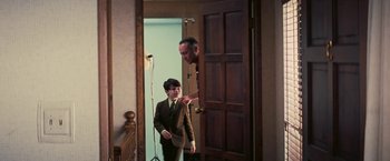 Movie still from “Licorice Pizza” (2021), directed by Paul Thomas Anderson – An older man and a young boy standing in front of a door; Medium shot, Over the shoulder angle
