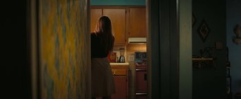 Movie still from “Licorice Pizza” (2021), directed by Paul Thomas Anderson – A woman standing in a kitchen looking into the oven; Medium shot, High angle