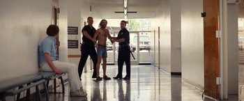 Movie still from “Licorice Pizza” (2021), directed by Paul Thomas Anderson – A group of men standing next to each other in a building; Wide shot, Low angle