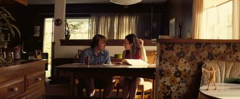 Movie still from “Licorice Pizza” (2021), directed by Paul Thomas Anderson – Two women are sitting at a table talking to each other; Medium shot, High angle