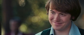 Movie still from “Licorice Pizza” (2021), directed by Paul Thomas Anderson – A person smiling with trees in the background; Close Up shot, Over the shoulder angle