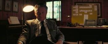 Movie still from “Licorice Pizza” (2021), directed by Paul Thomas Anderson – An older man in a suit and tie sitting in a chair; Medium shot, Over the shoulder angle