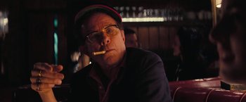 Movie still from “Licorice Pizza” (2021), directed by Paul Thomas Anderson – A man sitting in front of a bar smoking a cigarette; Close Up shot, Over the shoulder angle