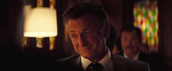 Movie still from “Licorice Pizza” (2021), directed by Paul Thomas Anderson – An older man wearing a suit and tie smiling; Close Up shot, Low angle