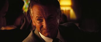 Movie still from “Licorice Pizza” (2021), directed by Paul Thomas Anderson – An older man wearing a suit and tie smiling; Close Up shot, Over the shoulder angle