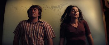 Movie still from “Licorice Pizza” (2021), directed by Paul Thomas Anderson – A man and a woman standing next to each other; Medium shot, Low angle