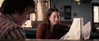Movie still from “Licorice Pizza” (2021), directed by Paul Thomas Anderson – A woman sitting at a table looking at papers; Medium shot, Over the shoulder angle