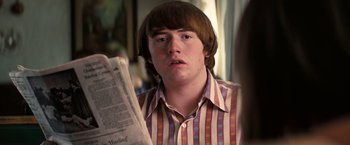 Movie still from “Licorice Pizza” (2021), directed by Paul Thomas Anderson – A young man reading a newspaper in a living room; Close Up shot, Over the shoulder angle