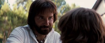 Movie still from “Licorice Pizza” (2021), directed by Paul Thomas Anderson – A man with long hair and a beard looking into the camera; Close Up shot, Over the shoulder angle