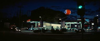 Movie still from “Licorice Pizza” (2021), directed by Paul Thomas Anderson – A gas station with cars parked in front of it at night; Extreme Wide shot, Low angle