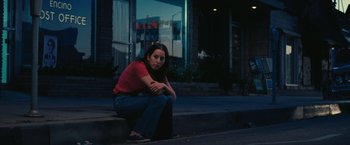 Movie still from “Licorice Pizza” (2021), directed by Paul Thomas Anderson – A woman sitting on the steps of a building; Medium shot, Low angle
