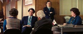 Movie still from “Licorice Pizza” (2021), directed by Paul Thomas Anderson – Two men in business suits sitting in front of two other men in business suits; Medium shot, Over the shoulder angle