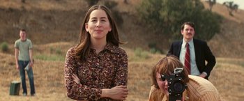 Movie still from “Licorice Pizza” (2021), directed by Paul Thomas Anderson – A woman standing in a field with her arms crossed; Medium shot, Over the shoulder angle