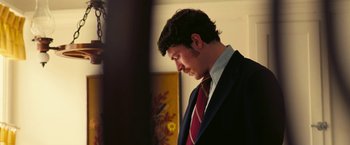 Movie still from “Licorice Pizza” (2021), directed by Paul Thomas Anderson – A man in a suit and a red tie looking down; Close Up shot, Low angle