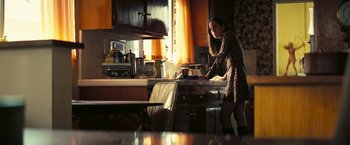 Movie still from “Licorice Pizza” (2021), directed by Paul Thomas Anderson – A woman standing at a kitchen counter preparing a meal; Medium shot, Low angle