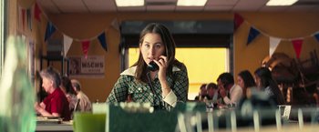Movie still from “Licorice Pizza” (2021), directed by Paul Thomas Anderson – A woman sitting at a table talking on a phone; Close Up shot, Over the shoulder angle