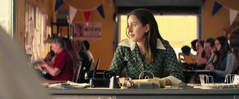 Movie still from “Licorice Pizza” (2021), directed by Paul Thomas Anderson – A woman sitting at a table in front of a phone; Medium shot, Over the shoulder angle