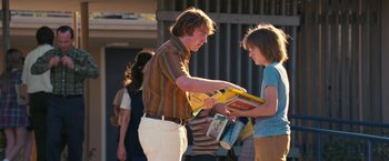 Movie still from “Licorice Pizza” (2021), directed by Paul Thomas Anderson – A man and a woman looking at books on a sidewalk; Medium shot, Over the shoulder angle