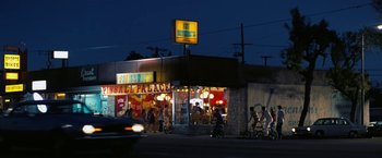 Movie still from “Licorice Pizza” (2021), directed by Paul Thomas Anderson – A group of people riding bikes in front of a restaurant; Extreme Wide shot, High angle