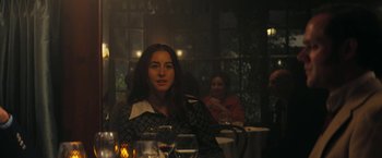Movie still from “Licorice Pizza” (2021), directed by Paul Thomas Anderson – A woman sitting in front of a table with wine glasses; Medium shot, Over the shoulder angle