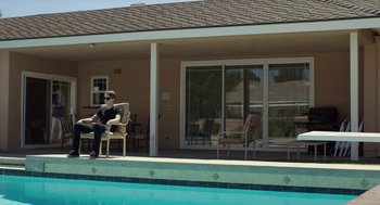Movie still from “Life After Beth” (2014), directed by Jeff Baena – A man sitting on a chair next to a swimming pool; Wide shot, High angle