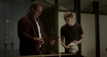Movie still from “Life After Beth” (2014), directed by Jeff Baena – A man and a boy are looking at a tablet computer; Medium shot, Low angle
