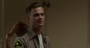 Movie still from “Life After Beth” (2014), directed by Jeff Baena – A man in a sheriff's uniform smiling for the camera; Close Up shot, Over the shoulder angle