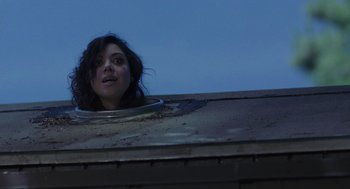 Movie still from “Life After Beth” (2014), directed by Jeff Baena – A woman looking out of a hole in the roof of a building; Close Up shot, Low angle