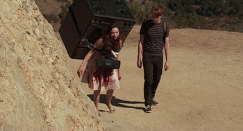 Movie still from “Life After Beth” (2014), directed by Jeff Baena – A woman in a white dress and a man in a black shirt carrying a suitcase; Wide shot, High angle