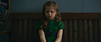Movie still from “Life Itself” (2018), directed by Dan Fogelman – A little girl in a green dress sitting on top of a wooden bench; Medium shot, High angle
