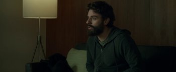 Movie still from “Life Itself” (2018), directed by Dan Fogelman – A man sitting on a couch looking at the camera; Medium shot, Over the shoulder angle